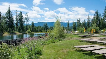 A lakeside view with picnic tables, a fenced area, and dense forest.