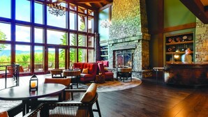 A spacious room with large windows, a stone fireplace, and a bar area. - Suncadia Resort (Cle Elum)