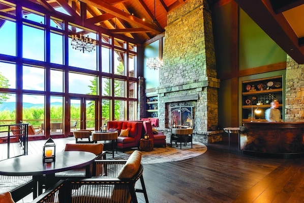 A spacious room with large windows, a stone fireplace, and a bar area. - Suncadia Resort (Cle Elum)