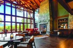 A spacious room with large windows, a stone fireplace, and a bar area.