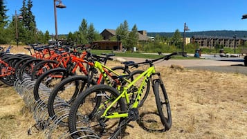 A row of bicycles parked on a grassy area with a building in the background.