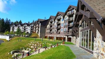Een hotel met meerdere verdiepingen, met balkons, een stenen gevel en een pad van steen dat naar de ingang leidt.