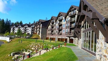 Un hotel de varios pisos con balcones, fachada de piedra y un camino de piedra que conduce a la entrada.