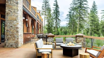 A patio with outdoor seating, a fire pit, and a view of tall trees.