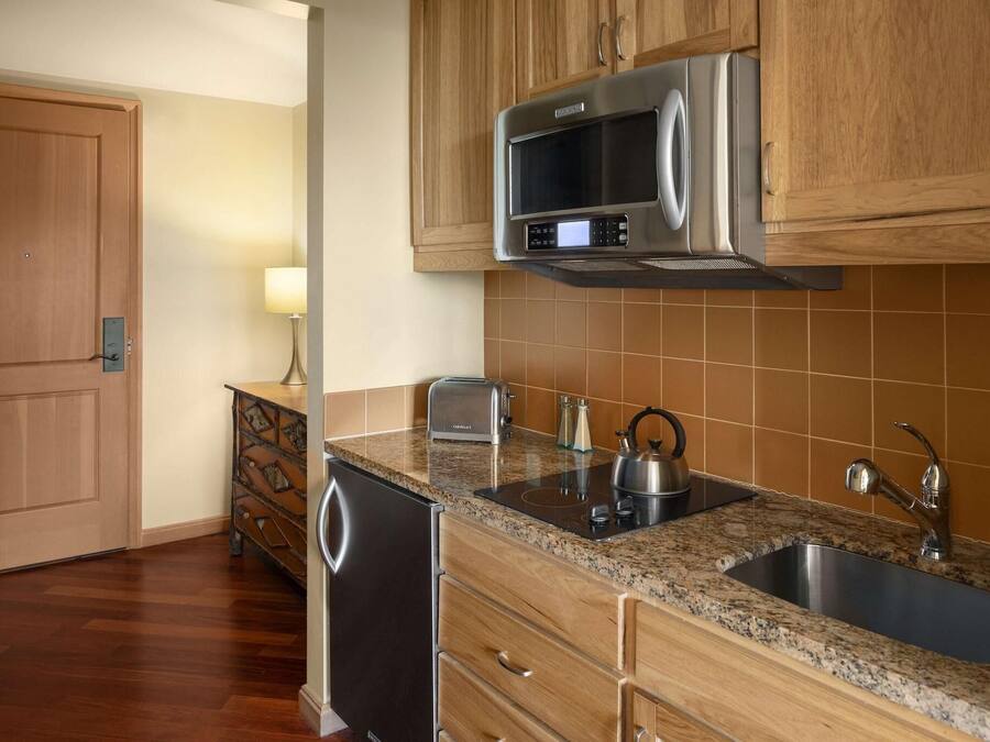A kitchen with wooden cabinets, a stainless steel microwave, a sink, and a dishwasher.
