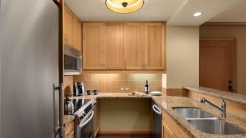 A compact kitchen with wooden cabinets, stainless steel appliances, granite countertops, and a built-in microwave.