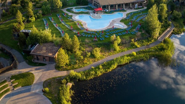 Un resort con piscina, un edificio grande y zona boscosa.