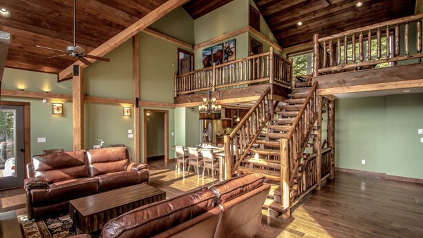 A spacious living area with a high ceiling, wooden staircase, leather sofas, and a dining area. - Spectacular Views, Private Estate , Hot Tub, Close to Everything (Intervale)