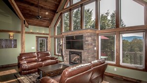 A spacious living room with leather sofas, a fireplace, large windows, and a wooden ceiling. - Spectacular Views, Private Estate , Hot Tub, Close to Everything (Intervale)