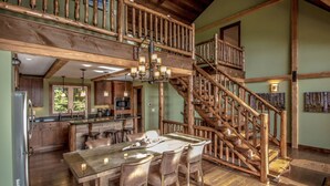 A rustic interior with a wooden staircase, a dining area with a large table and chairs, and a kitchen with wooden cabinets and a built-in oven. - Spectacular Views, Private Estate , Hot Tub, Close to Everything (Intervale)