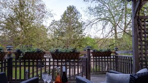 An outdoor patio with wicker furniture, a wooden table, and potted plants. - Steps to Main Street, Picton w Sandbanks Pass, Bbq and Large Private Back Yard (Picton)
