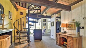 Un escalier mène à une mezzanine d’où l’on peut admirer la vue sur l’extérieur. On y trouve un bureau avec des tiroirs et une lampe, une chaise, ainsi qu’un panier posé sur le sol.