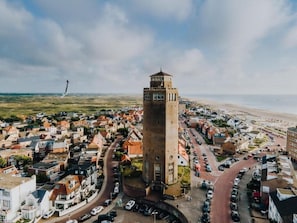 Un pueblo costero con una torre destacada, calles estrechas y una playa al fondo.