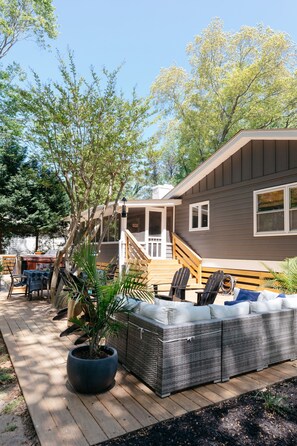 A deck with outdoor furniture, a potted plant, and a house with a covered porch. - Peaceful Beach Retreat in Southern Shores.Beach Front Parking Passes included (Kitty Hawk)