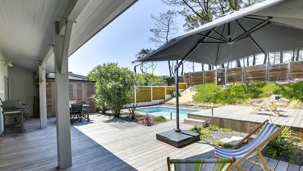 A covered outdoor deck with a pool, a grill, and a hammock.