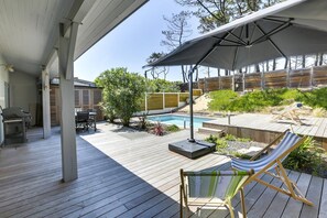 Une terrasse extérieure couverte avec une piscine, un barbecue et un hamac.