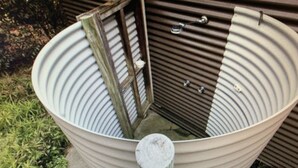 A large, empty, white, ribbed bathtub with a wooden door and metal handles.