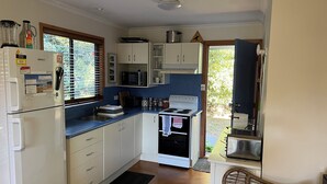 A compact kitchen with white cabinets, a built-in microwave, a stove, and a refrigerator.