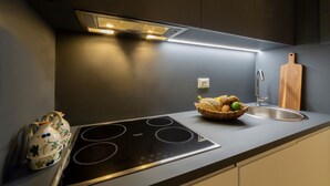 Et moderne køkken med et indbygget komfur, en vask samt en kurv med brød og æg.