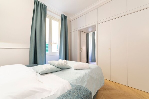 A bedroom with a bed, curtains, a wardrobe, and a window.