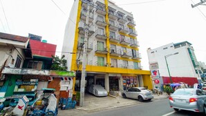 A multi-story building with balconies, a clear storefront, and a parked car in front. - ZEN Rooms Palanan (Makati)