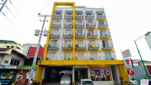 A multi-story building with a yellow and white facade, multiple balconies, and a ground-level entrance. - ZEN Rooms Palanan (Makati)