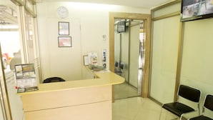 A reception area with a counter, chairs, a clock, and a security camera. - ZEN Rooms Palanan (Makati)