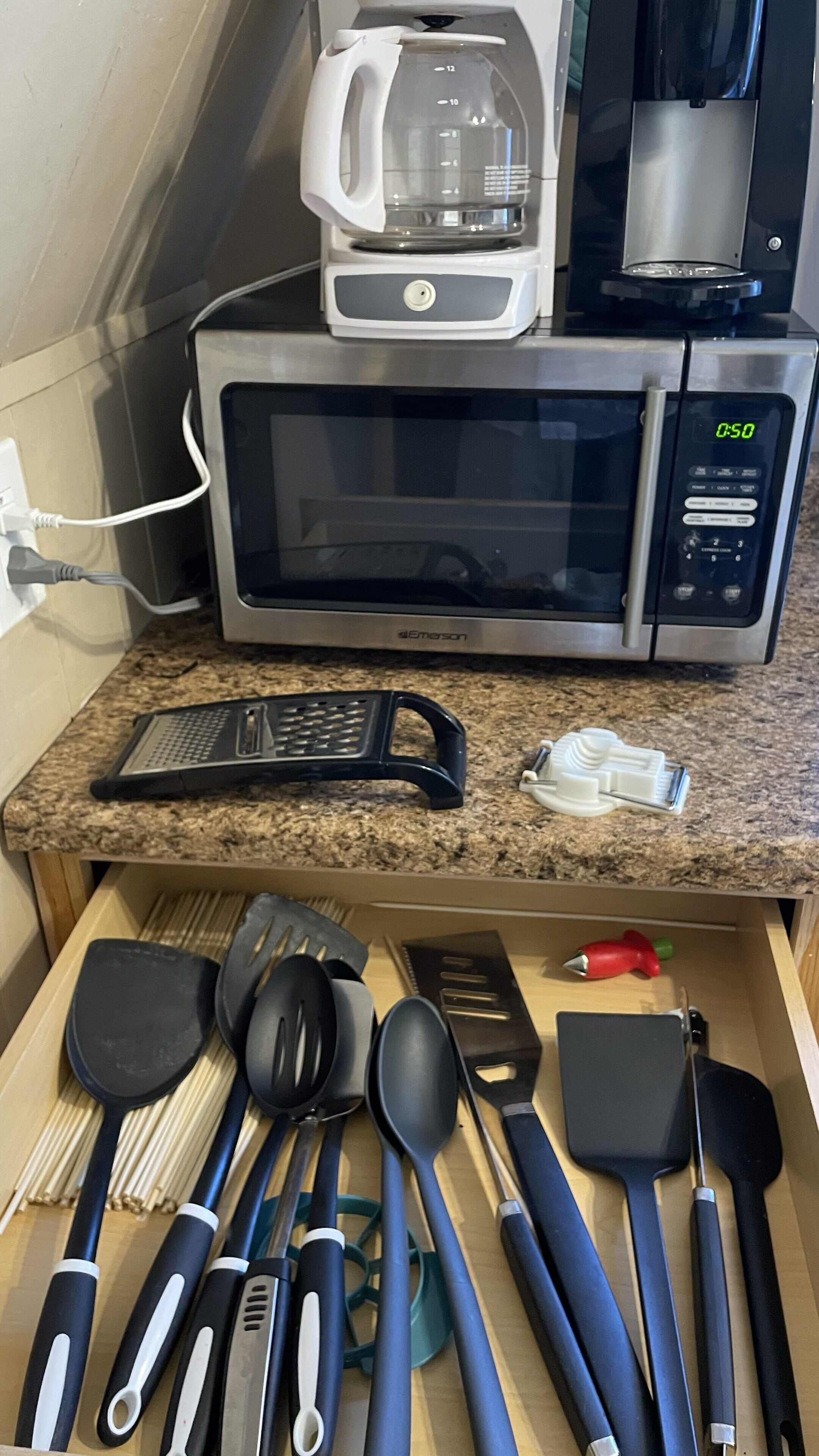 Een keuken met een magnetron, koffiezetapparaat en diverse keukengerei.