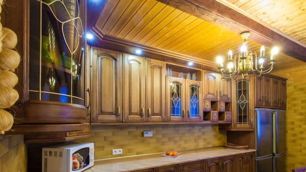 Eine Küche mit Holzschränken, einer eingebauten Mikrowelle und einem Edelstahlkühlschrank.