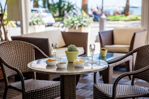 A round table with wicker chairs, a small potted plant, and two glasses of water. - Hotel Vesuvio (Rapallo)