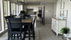 Una cucina moderna con mobili bianchi, un'area pranzo con tavolo in legno e sedie nere, e una scala che conduce a un altro livello.