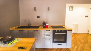 Une cuisine de taille réduite, équipée d’un évier, d’une cuisinière et de deux placards.