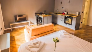Une chambre d’hôtel de taille réduite comprenant un lit, un petit coin salon, une kitchenette et un téléviseur.