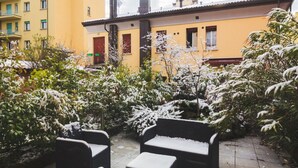 Une cour avec des sièges extérieurs et des plantes recouvertes de neige.