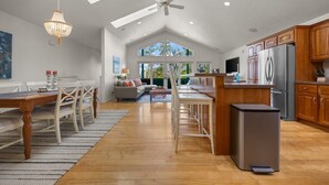 Una cocina amplia con armarios de madera, un refrigerador de acero inoxidable y un comedor con mesa y sillas de madera.