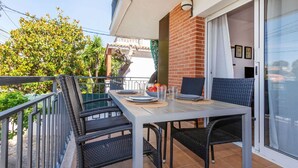 A balcony with a table, chairs, and a sliding glass door.