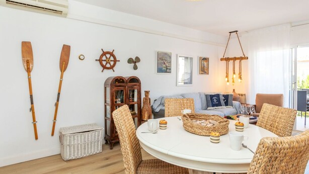A cozy room with a round table, wicker chairs, a wooden cabinet, and nautical decor.