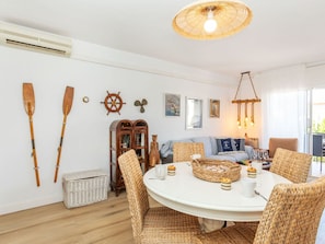 Una habitación acogedora con una mesa redonda, sillas de mimbre, un aparador de madera y decoración náutica.