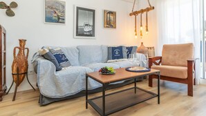 A living room with a striped sofa, a wooden coffee table, a chair, and nautical-themed wall art.