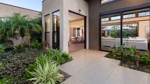 A modern house with a patio area, a dining room, and a living room with a sofa and chairs. - Spectacular luxury golf course view home in the heart of the Mauna Lani resort (Kamuela)