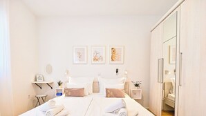 Una camera d'albergo con due letti, una scrivania con sedia, un piccolo tavolo e un armadio.