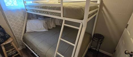 Een stapelbed met een ladder, een klein krukje en een deur met een hendel.