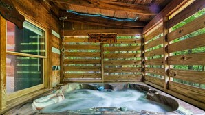 Une cabane en bois dotée d’un bain à remous, de murs en bois et d’une enseigne indiquant : « The Smoky Mountain Door ».