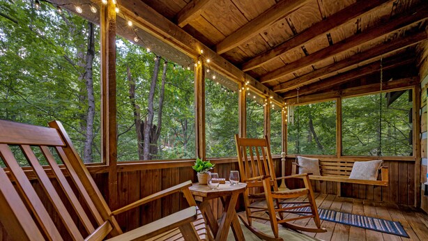 Une cabane en bois avec une véranda, des meubles en bois et des guirlandes lumineuses.
