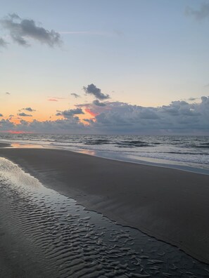 Une plage au sable humide et aux vagues douces.