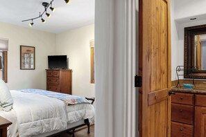 A bedroom with a bed, a dresser, a television on a cabinet, and a wooden door. - Right on the Plaza next to O'keeffe Museum (Santa Fe)