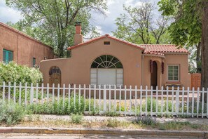 A single-story building with a red-tiled roof, a white picket fence, and a small porch with a bench. - Right on the Plaza next to O'keeffe Museum (Santa Fe)