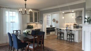 Een ruime keuken met een centraal eiland, een houten eettafel met stoelen, en een kroonluchter.