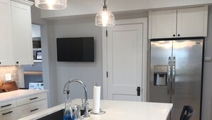 Een moderne keuken met een centraal eiland, roestvrijstalen apparatuur en hangende lampen.
