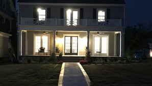 Een tweelaags huis met een veranda, een kleine tuin en een pad naar de ingang.